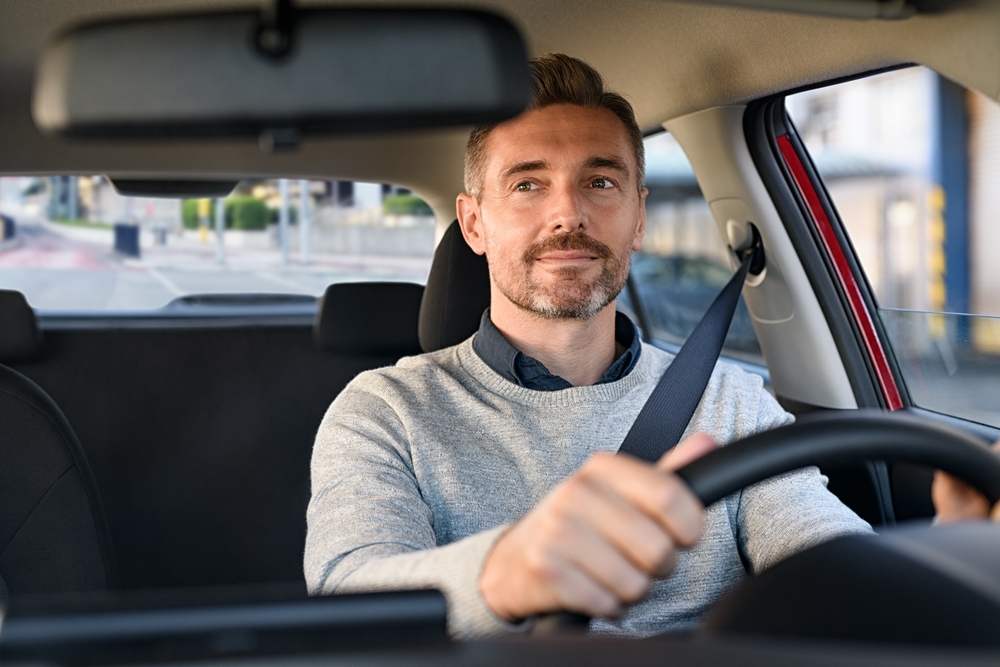 Mid,Adult,Man,Smiling,While,Driving,Car,And,Looking,At